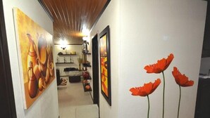 Un couloir orné d’œuvres d’art sur les murs, un escalier et, au fond, un espace cuisine.