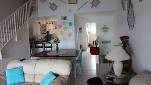 A living room with a sofa, a dining table, and a staircase. - Beautiful, Spacious 3 Story, Waterfront Condo Bimini, Bahamas - Sleeps 10 (South Bimini)