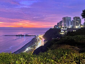A coastal cityscape at sunset with illuminated buildings and a beach. - Stunning, Luxury City and Ocean View Apartment in the Heart of Miraflores (Miraflores)