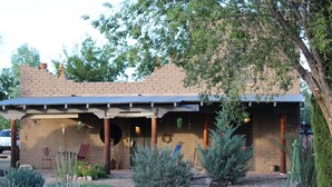 A rustic building with a covered patio, brick walls, and a garden with various plants and a bench. - HiddenOasisBandB   " A Bed & Breakfast Community" (Dragoon)