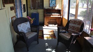 A cozy room with wicker chairs, a blue cabinet, and a wooden piano. - HiddenOasisBandB   " A Bed & Breakfast Community" (Dragoon)