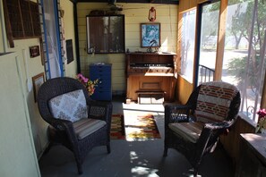 A cozy room with wicker chairs, a blue cabinet, and a wooden piano. - HiddenOasisBandB   " A Bed & Breakfast Community" (Dragoon)