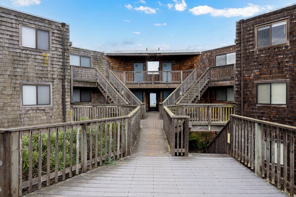 Un pasillo de madera que conduce a un edificio con varios balcones y ventanas.