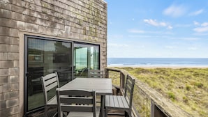 Un balcón con mesa y sillas con vista a una playa.
