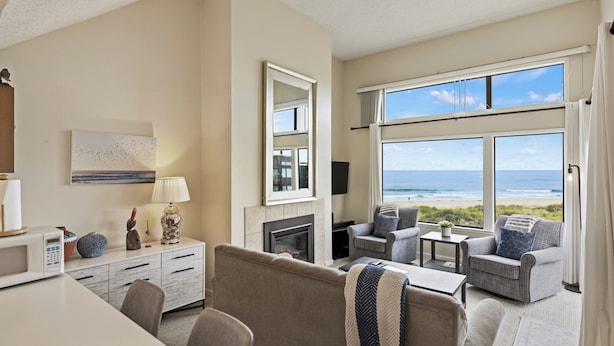 Habitación de hotel moderna con vista a la playa, chimenea y zona de estar también con vista.