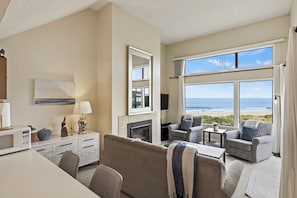 Habitación de hotel moderna con vista a la playa, chimenea y zona de estar también con vista.