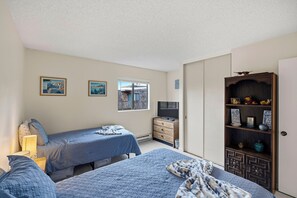 A bedroom with two beds, a TV, and a bookshelf.