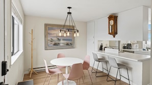 Una cocina moderna con encimera blanca, un reloj de madera y un cuadro en la pared.