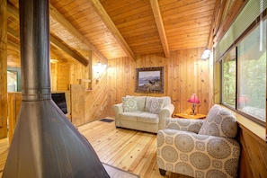 Cozy seating area with a fireplace, sofa, armchair, and artwork, offering a comfortable space to relax.