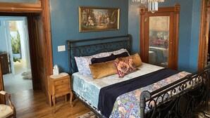 Un dormitorio con una cama, una mesita de noche, un espejo y una araña.