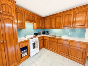 Een keuken met houten kasten, een fornuis, een magnetron en een spoelbak.