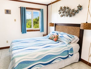 Un dormitorio con cama, ventana con cortinas, lámpara de pared y un adorno en la pared.
