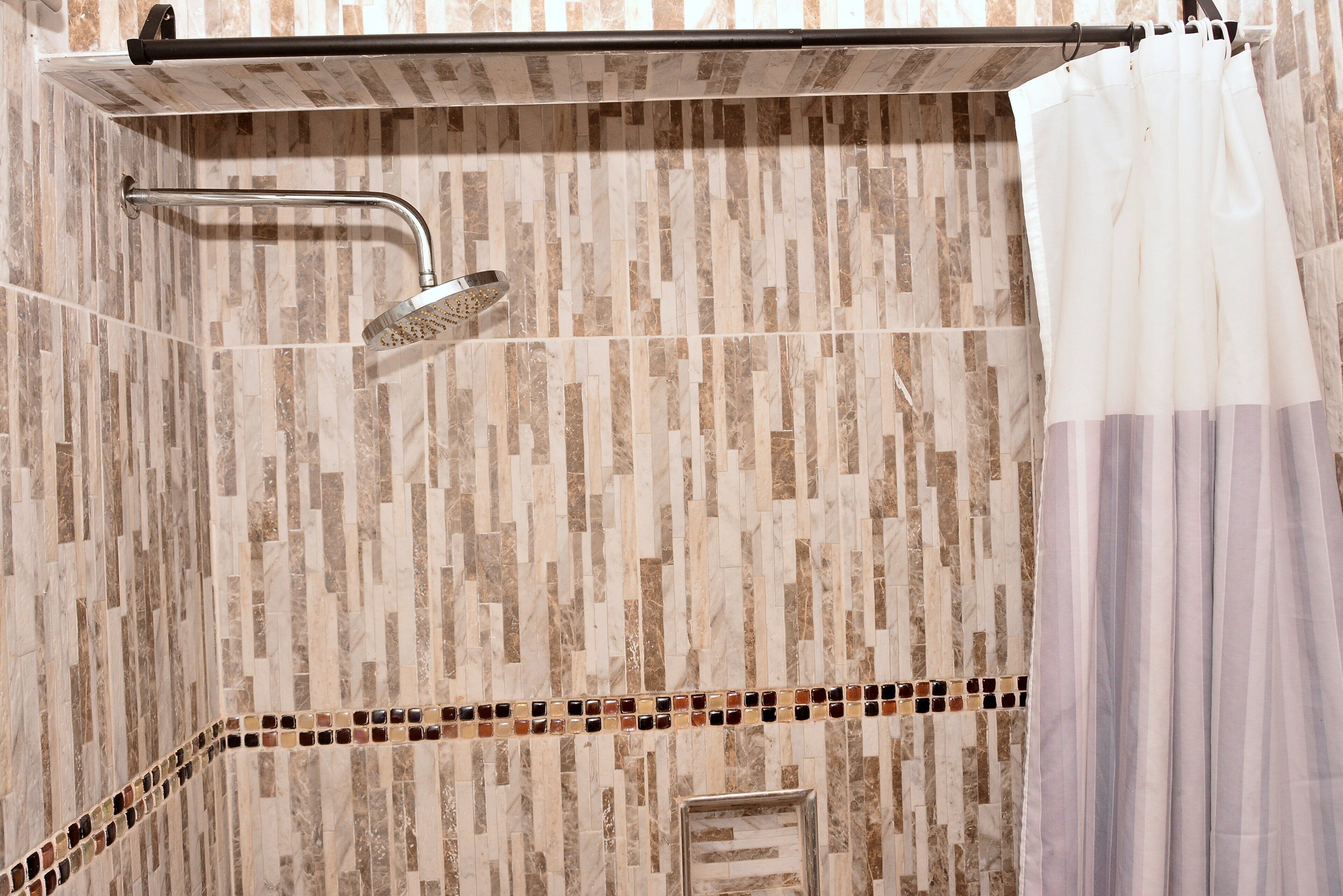 A shower area with a rain showerhead, a towel rack, and a shower curtain.