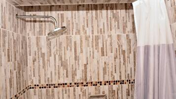 A shower area with a rain showerhead, a towel rack, and a shower curtain.