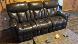 A dark brown leather sofa with a wooden coffee table in front, featuring a candle and a glass. - SAVE!  ROMATIC  GATLINBURG   GETAWAY!!    (Gatlinburg)