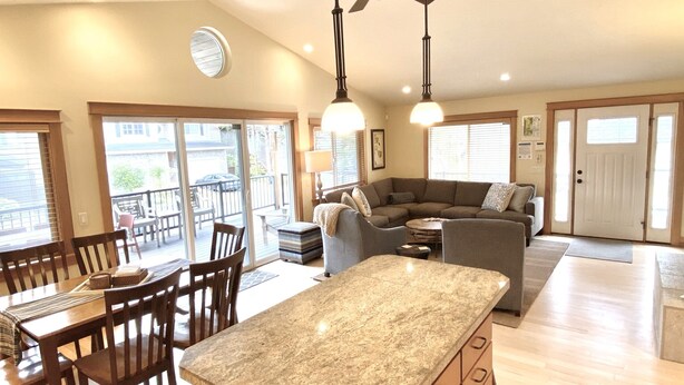 A spacious kitchen with a central island, wooden cabinets, and a dining area with chairs and a table.
