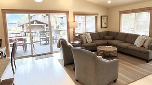 A spacious living room with a large sectional sofa, a round coffee table, and a dining area with a table and chairs.