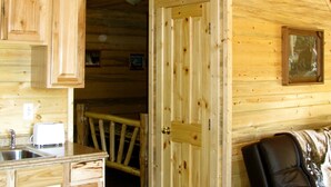 A wooden cabin interior with a kitchen area, a dining table, and a sofa. - A little heavenly peace, cabin No. 2 (Polebridge)