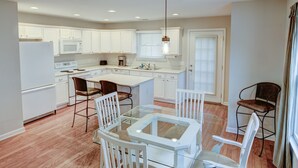 Una cocina moderna con armarios blancos, una mesa de comedor de vidrio y una isla central.