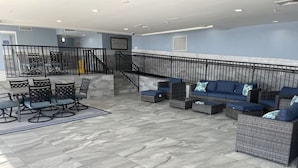 A spacious indoor area with a marble floor, wicker furniture, and a staircase.