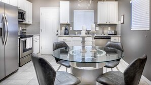 Een moderne keuken met een glazen eettafel, roestvrijstalen apparatuur en leren stoelen.