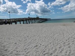 Una playa con un muelle de madera que se adentra en el océano.
