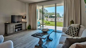 A living room with a flat-screen TV, a coffee table, and a sofa. - Pool Front at High Pointe Resort-Ground Floor Unit (Panama City Beach)