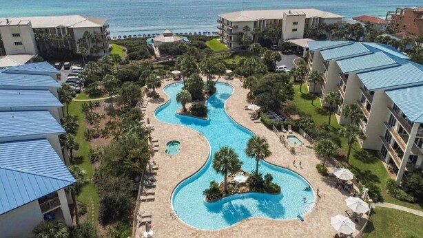 A resort with a winding pool, beachfront view, and multiple buildings with blue roofs. - Pool Front at High Pointe Resort-Ground Floor Unit (Panama City Beach)