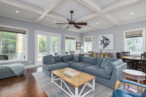 A spacious living room with a large sectional sofa, a wooden coffee table, and a ceiling fan. - DESIGNER LUXURY DECOR, SALTWATER POOL, HUGE WALK-IN SHOWER, PINGPONG, ELEVATOR, WALK TO BEACH (Hilton Head Island)