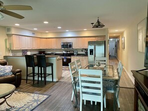 A modern kitchen with a central island, stainless steel appliances, and a dining area with a glass table and chairs.