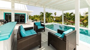 Un espacio exterior cubierto con piscina, mobiliario de mimbre y vistas del paisaje circundante.