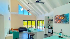 Una cocina amplia con una isla central, taburetes de bar y un ventilador de techo.