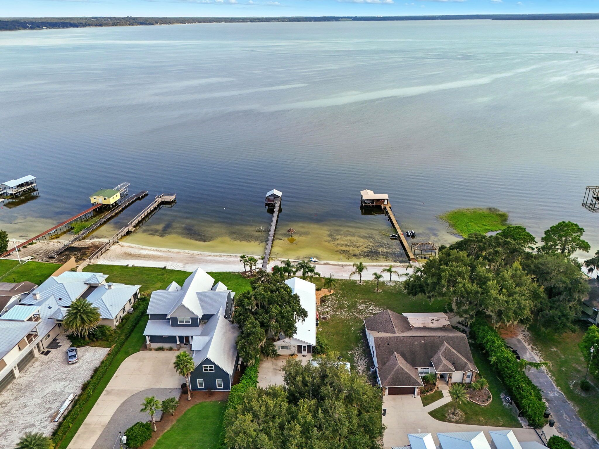 Vue aérienne d’une zone résidentielle côtière, avec des maisons, des quais et une plage.