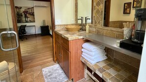 Une salle de bain avec un grand miroir, un meuble-lavabo en bois, un évier et un porte-serviettes.