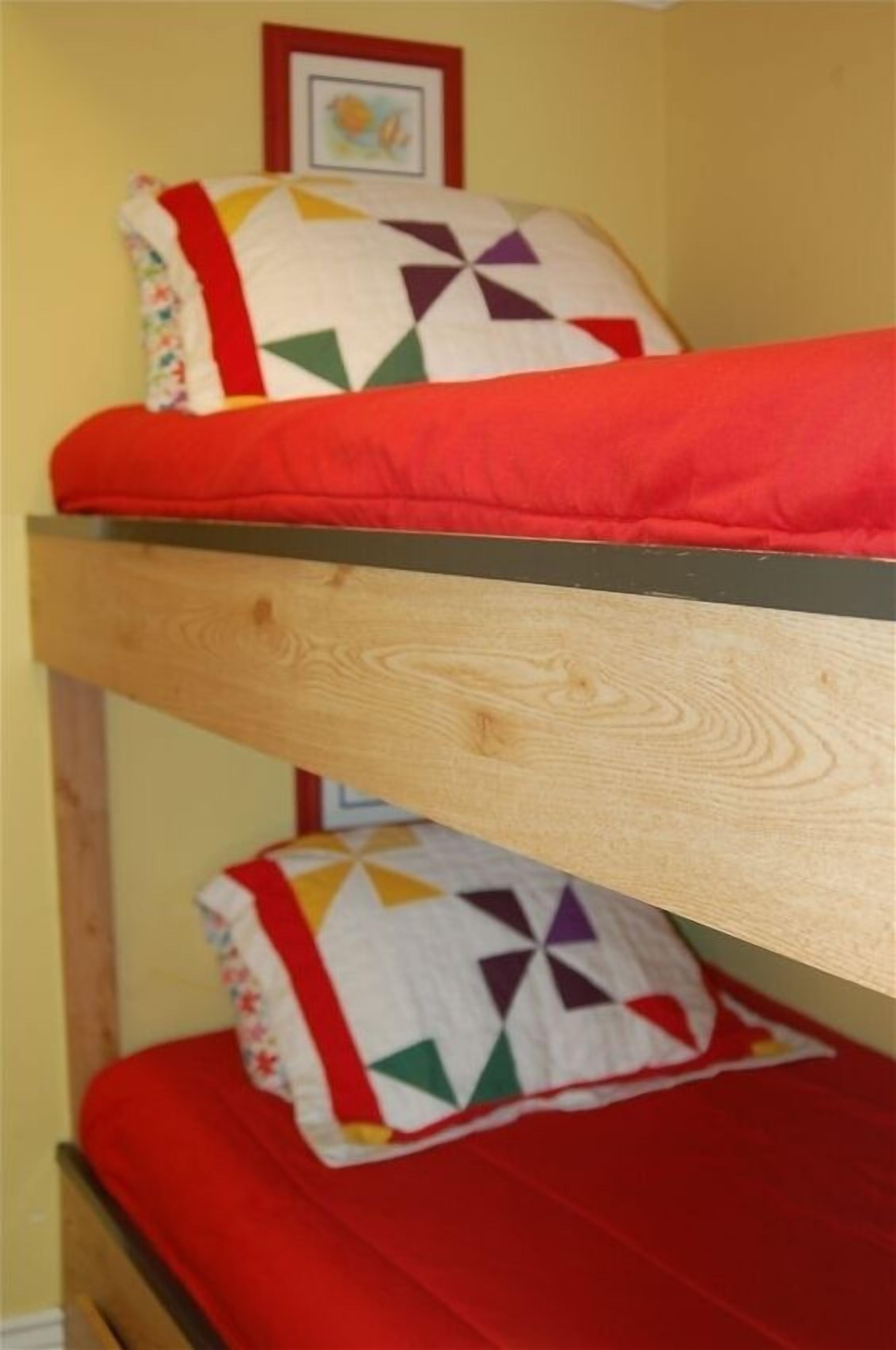 Un lit superposé avec un matelas rouge et une couette à motifs géométriques.
