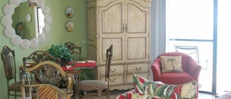 A room with a dining table, chairs, a cabinet, and a red armchair.