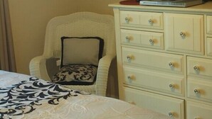A bedroom with a bed, a chair, a dresser, and a television.