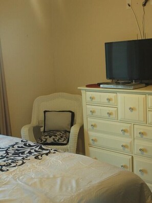Une chambre à coucher avec un lit, une chaise, une commode et un téléviseur.
