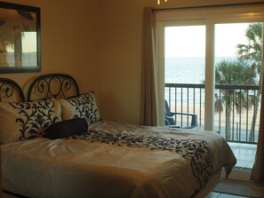 A bedroom with a bed, a balcony with a view of the sea, and a chair. - Seabreeze-Maravilla Gulf Front 2 Bedroom Condo/Dog Friendly (Galveston)