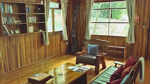 Un intérieur en bois avec une bibliothèque, un coin salon et des fenêtres.