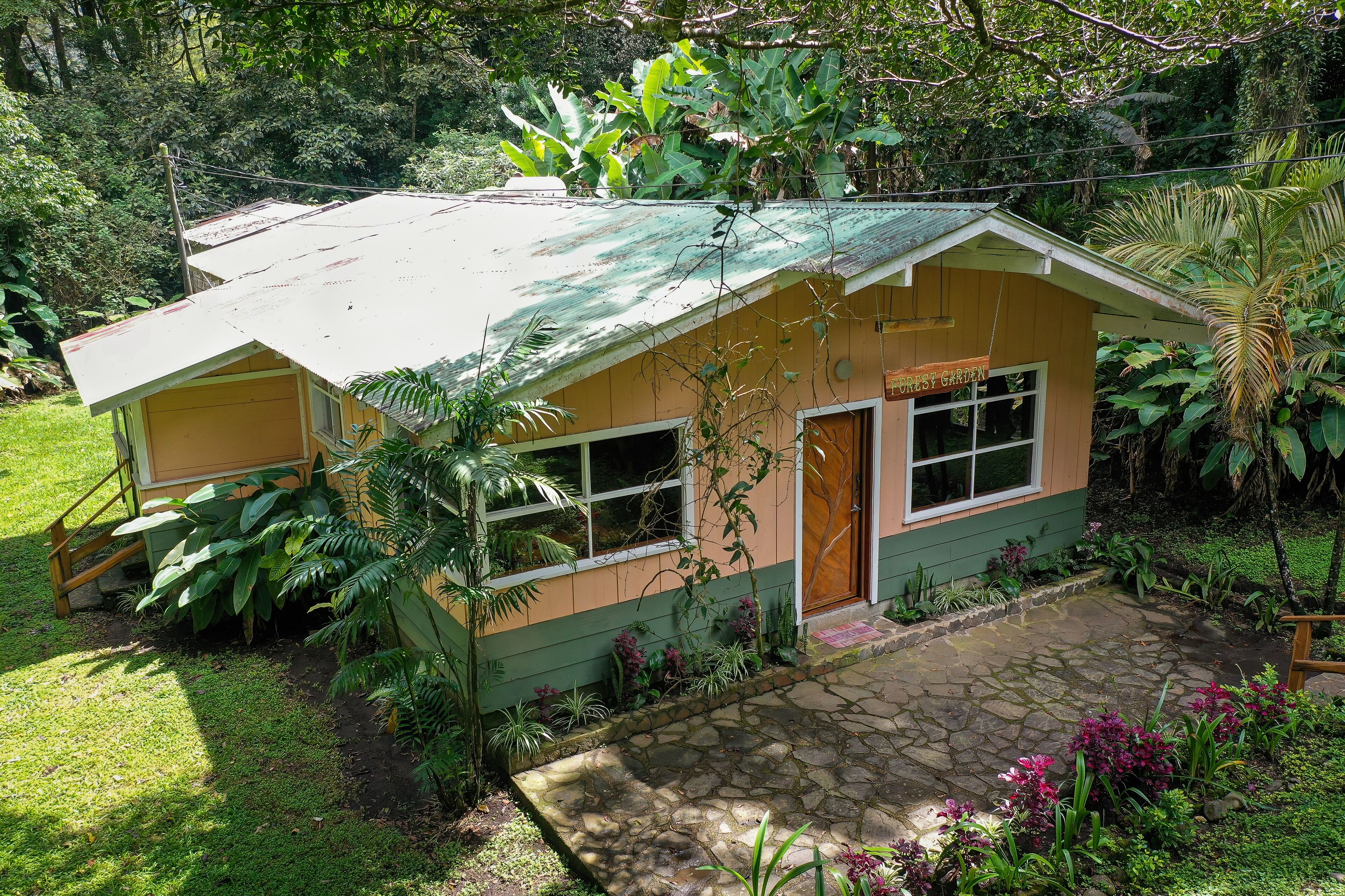 Una casita de una sola planta con techo verde y un letrero que dice 