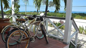 Ein Fahrrad auf einer gefliesten Terrasse mit Blick auf das Meer und Palmen.