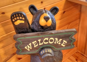 Un letrero de madera con una figura de oso y la palabra 'WELCOME'.