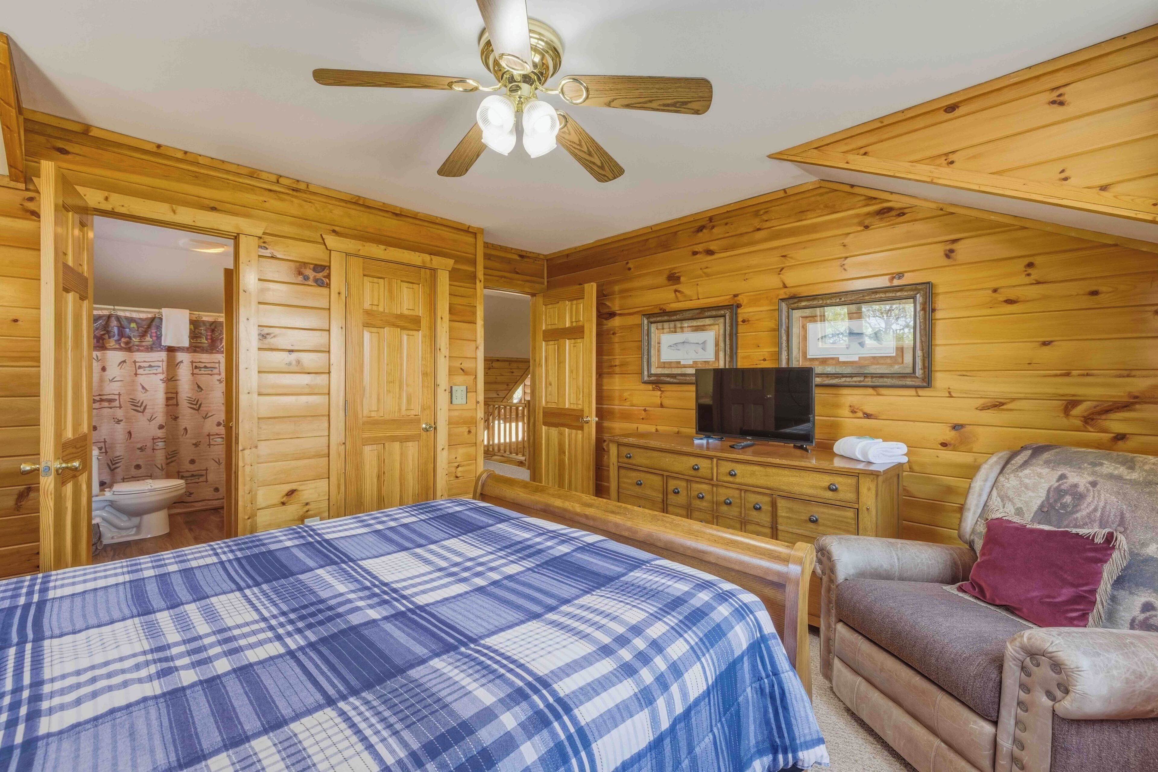 Quarto de cabana de madeira com cama, televisão e uma cadeira.