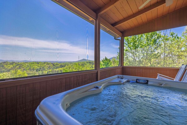 A hot tub with a view of a forest and mountains.