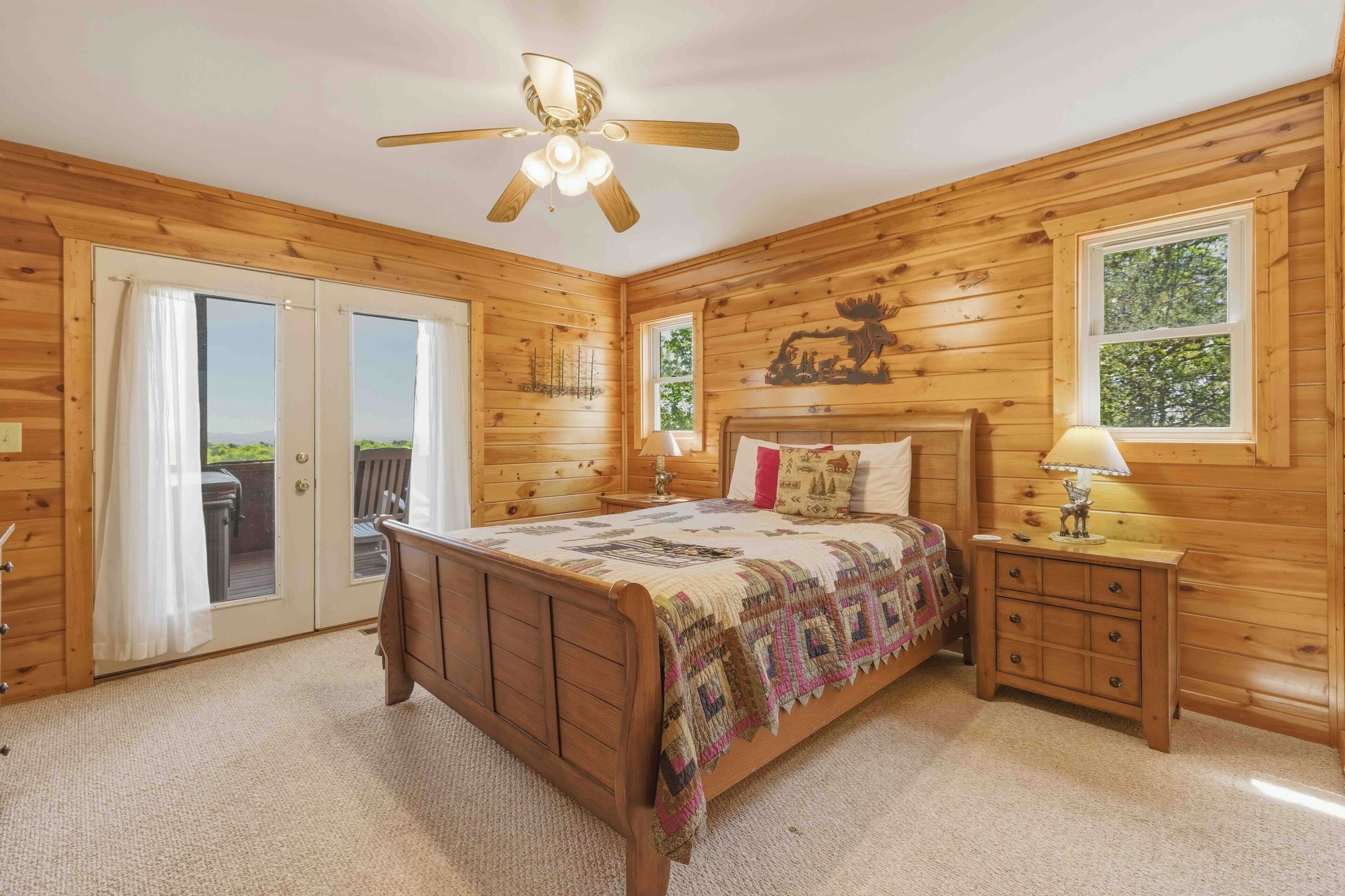 A wooden room with a bed, a nightstand, a lamp, and a ceiling fan.