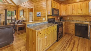 Interior de una cabaña de madera con cocina, comedor y sala de estar.