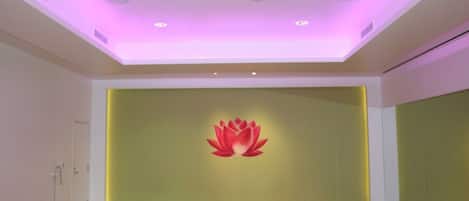 A room with a wooden floor, a wall with a lotus flower mural, and a ceiling with recessed lighting.