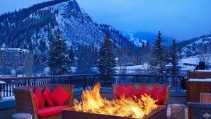 A fire pit with wicker furniture and red cushions on a balcony overlooking a snowy mountain. - CRBC - Best View in Resort! Ski In/Out, 2 Queen Beds, Spa, Ski Valet, PvtBalcony (Avon)