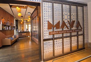 A modern Mexican restaurant interior with a wooden bench seating area and a patterned wall with the restaurant's name. - Charlie's Slopeside: Ski-In/Out, Ski Valet, Resort Amenities, Pool + Hot Tubs (Avon)